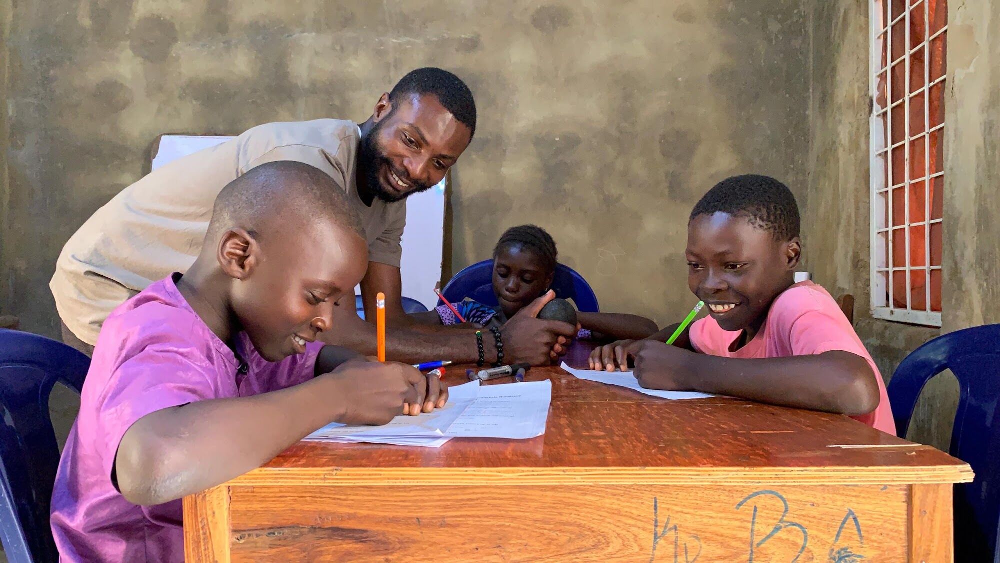 A tutor encouraging two boys with their work